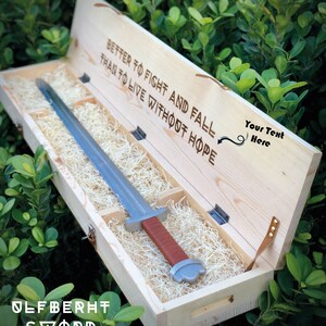 May include: A wooden box with a sword inside. The box is open and the sword is visible. The box has the text "Better to fight and fall than to live without hope" and "Ulfberht Sword" engraved on it.