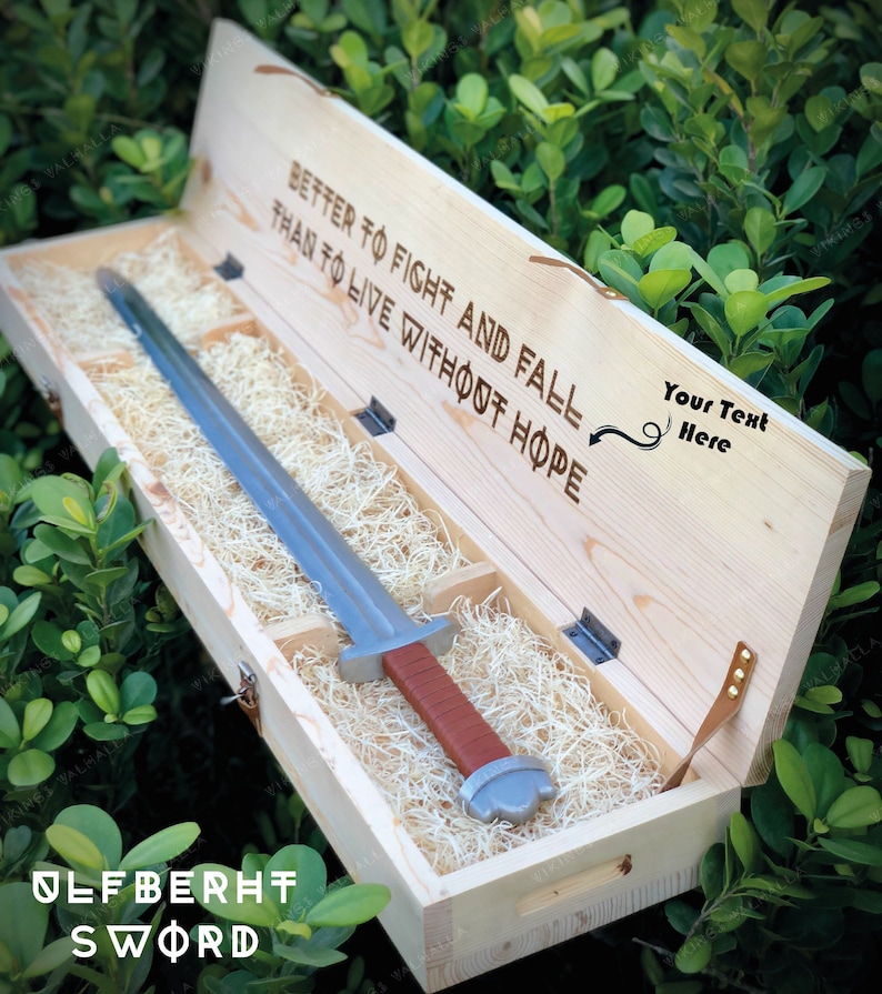 May include: A wooden box with a sword inside. The box is open and the sword is visible. The box has the text "Better to fight and fall than to live without hope" and "Ulfberht Sword" engraved on it.