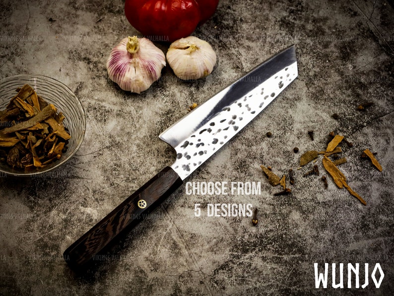 Pu&ograve; includere: Un coltello da cucina con manico nero e lama argentata con finitura martellata. Il coltello &egrave; appoggiato su una superficie grigia testurizzata con spezie sparse intorno. Il testo "Choose from 5 designs" &egrave; stampato sulla superficie. Il testo "WUNJO" &egrave; stampato nell'angolo in basso a destra dell'immagine.