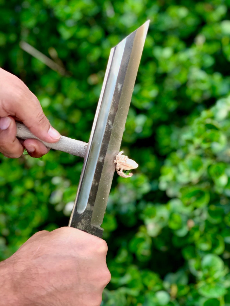 K&ouml;nnte beinhalten: Eine Person verwendet ein scharfes, silbernes Messer, um ein St&uuml;ck Holz zu schnitzen.