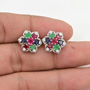 Könnte beinhalten: Ein Paar silberne Ohrstecker in Blumenform mit roten, grünen und blauen Edelsteinen.