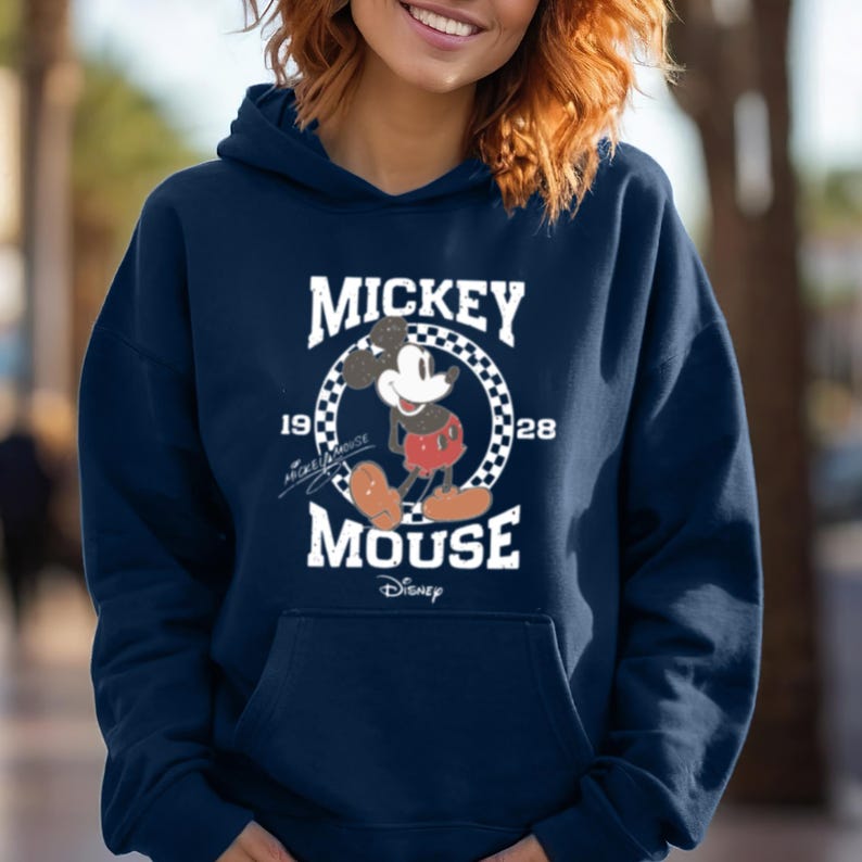 Puede incluir: Una sudadera con capucha azul marino con un gr&aacute;fico blanco de Mickey Mouse. El gr&aacute;fico presenta a Mickey Mouse en su pose cl&aacute;sica con el texto "Mickey Mouse" y "1928" arriba y abajo de &eacute;l. El texto "Disney" est&aacute; en la parte inferior del gr&aacute;fico.
