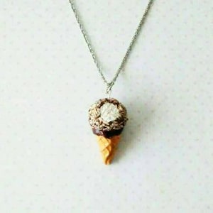 May include: A silver chain necklace with a brown and white ice cream cone pendant.