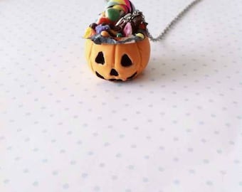 Puede incluir: Un collar de temática de Halloween con una pequeña calabaza naranja con una cara tallada, llena de caramelos coloridos y rematada con una piruleta en espiral.