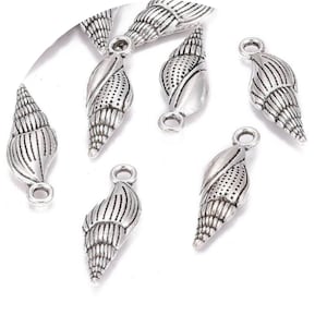 Op de afbeelding: Zilverkleurige metalen schelpbedels met een gedetailleerd ontwerp. De bedels hebben een lus aan de bovenkant om aan sieraden of andere knutselwerkjes te bevestigen.