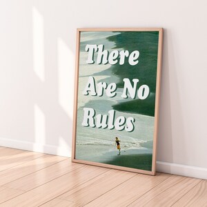 May include: A framed print with a green and white background featuring the text "There Are No Rules" in white. A person is walking on a beach in the background.