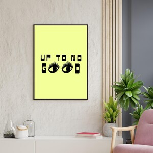 May include: A black framed print with a yellow background and the text "UP TO NO GOOD" in black letters. Two black eyes with eyelashes are below the text.