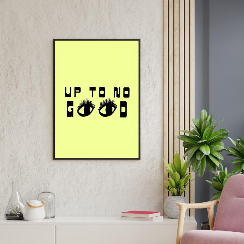 May include: A black framed print with a yellow background and the text "UP TO NO GOOD" in black letters. Two black eyes with eyelashes are below the text.