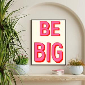May include: A framed print with a white background and red outline. The print says "BE BIG" in large, pink letters.