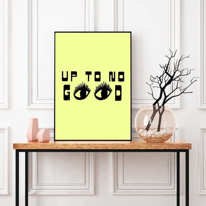 May include: A yellow poster with black text that reads "UP TO NO GOOD" with two black eyes with eyelashes below the text.