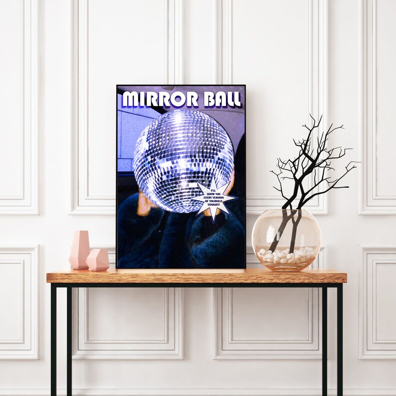 May include: A poster with the text "MIRROR BALL" in a retro font. A disco ball is in the center of the poster, partially obscured by a person wearing a blue fur coat. The text "I'LL SHOW YOU A REFLECTION OF YOURSELF TONIGHT" is in a white starburst shape.