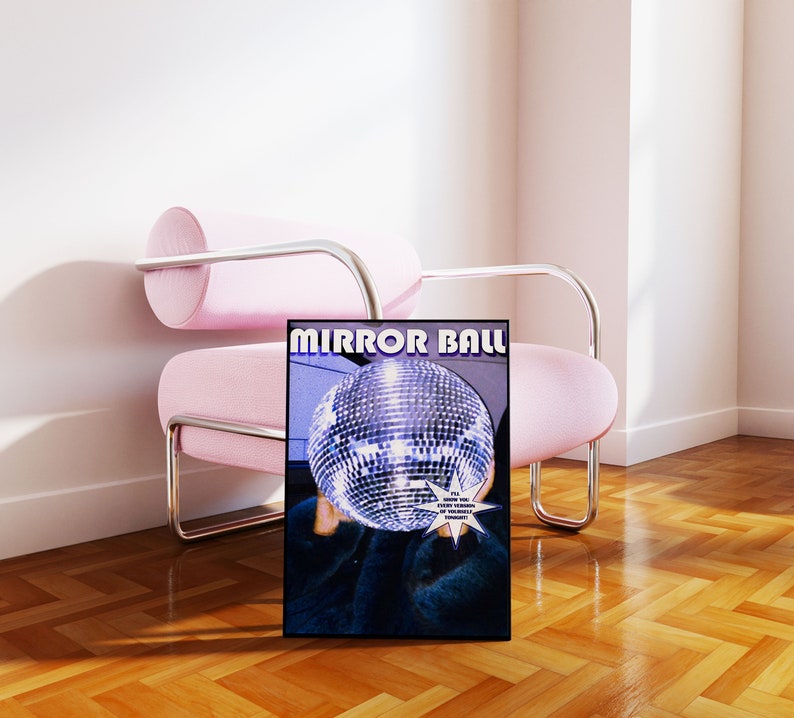 May include: A black and white poster with the text "MIRROR BALL" in bold, blue letters. The poster features a large, silver disco ball with a person's hand holding it in front of their face. The background is a blurry image of a room.