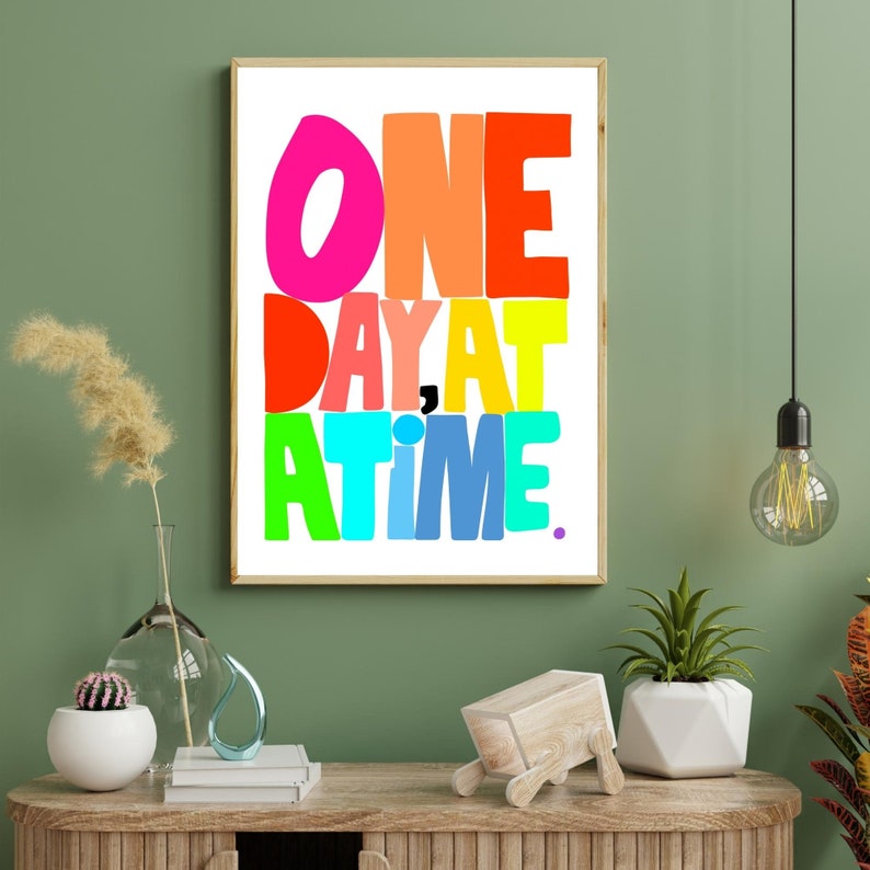 May include: A colorful typography print with the text "ONE DAY AT A TIME." The letters are in different colors, including pink, orange, yellow, green, blue, and purple.