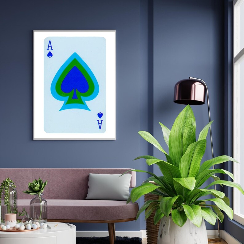 May include: A framed print of the Ace of Spades playing card. The card is blue, green, and black with a white background. The card is framed in a white frame.