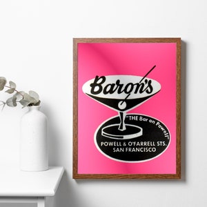 Puede incluir: Una impresi&oacute;n enmarcada sobre un fondo rosa con una ilustraci&oacute;n en blanco y negro de una copa de martini con el texto "Baron's" y "The Bar on Powell" en un c&iacute;rculo debajo de la copa. El texto "Powell & O'Farrell Sts. San Francisco" est&aacute; debajo del c&iacute;rculo.