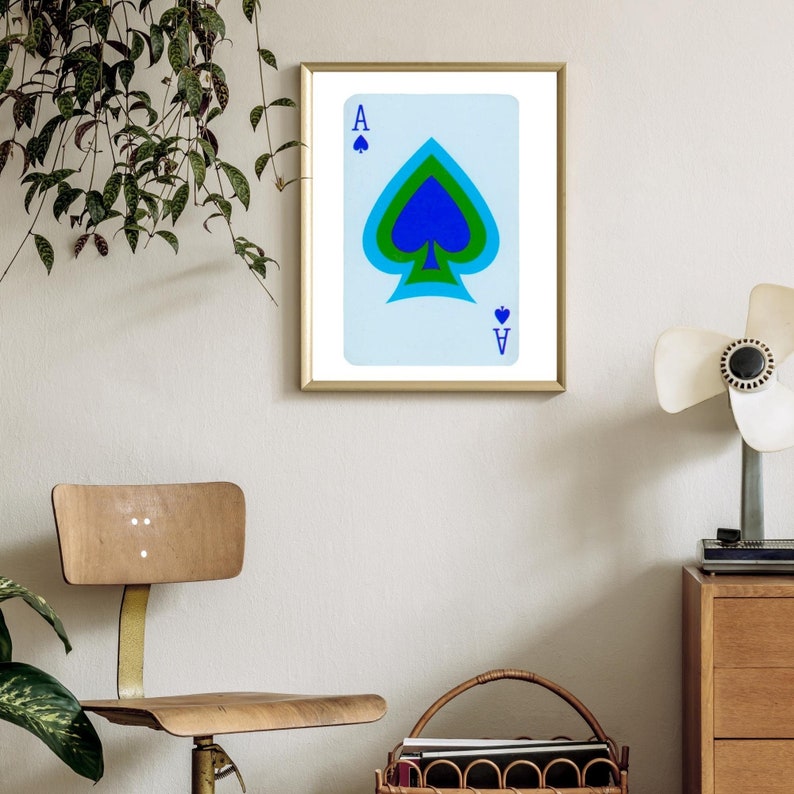 May include: A framed print of a playing card, the Ace of Spades, with a blue, green, and white design.
