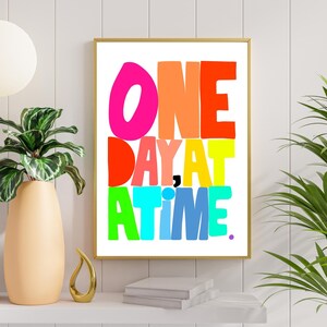 May include: A colorful typography print with the text "ONE DAY AT A TIME." The letters are in different colors, including pink, orange, red, yellow, green, blue, and purple.