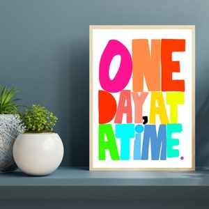May include: A colorful framed print with the text "ONE DAY AT A TIME." The letters are in different colors, including pink, orange, red, yellow, green, blue, and purple.