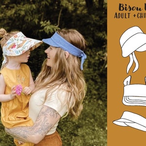 Könnte beinhalten: Eine Frau und ein Kind tragen bunte Visier. Die Visier sind in Erwachsenen- und Kindergrößen erhältlich. Der Text "Bisou Visor ADULT + CHILD SIZE" wird auf einem braunen Hintergrund angezeigt.