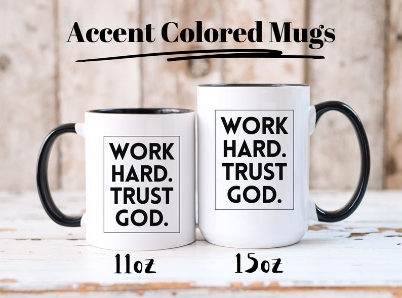 May include: Two white accent-colored mugs with black handles and rims. The mugs have the text "WORK HARD. TRUST GOD." in a black box. The smaller mug is 11oz, and the larger mug is 15oz. The words "Accent Colored Mugs" are at the top.