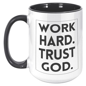 May include: White ceramic mug with a black handle and interior. The mug features the text "WORK HARD. TRUST GOD." in bold black letters within a black-lined rectangle. A motivational and inspirational item.