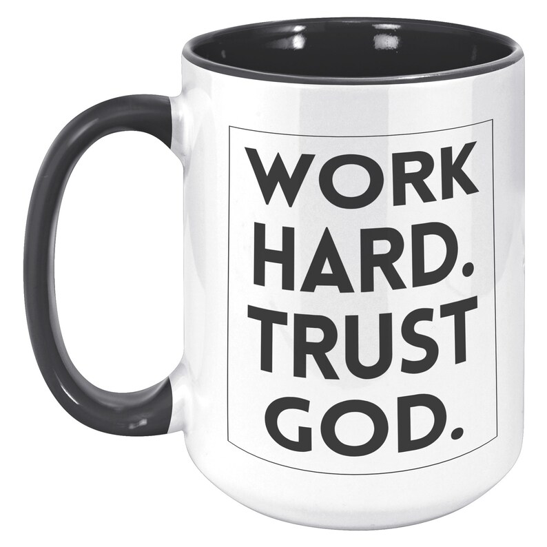 May include: White ceramic mug with a black handle and interior. The mug features the text "WORK HARD. TRUST GOD." in bold black letters within a black-lined rectangle. A motivational and inspirational item.