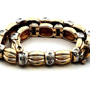 May include: A gold and silver bracelet with a chain link design and small clear stones. The bracelet has a clasp closure.