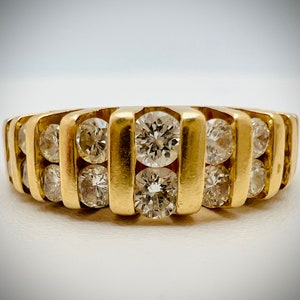 May include: A gold band ring with multiple rows of round diamonds.
