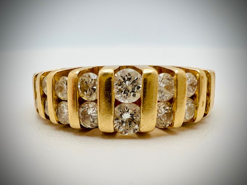 May include: A gold band ring with multiple rows of round diamonds.