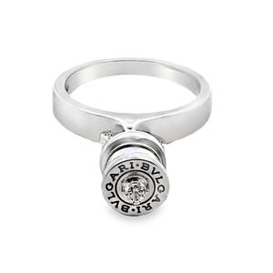 Puede incluir: Un anillo plateado con un diseño circular y una sola gema transparente. El anillo presenta el texto grabado "BVLGARI" alrededor de la gema. El anillo está sobre un fondo blanco.