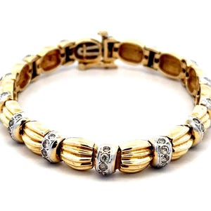 May include: A gold bracelet with a braided design and small clear stones set in the metal. The bracelet has a clasp closure.
