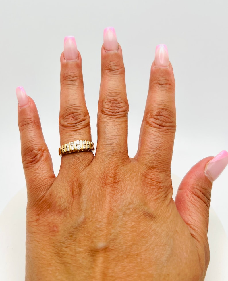 May include: A gold band ring with a row of small diamonds set in the band.