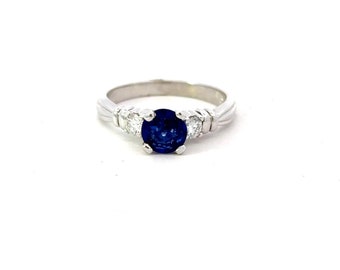 May include: A platinum ring with a blue sapphire center stone and two smaller diamond accents.