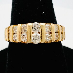 May include: A gold band ring with a row of round diamonds set in a channel setting.