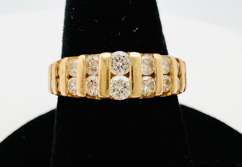 May include: A gold band ring with a row of round diamonds set in a channel setting.