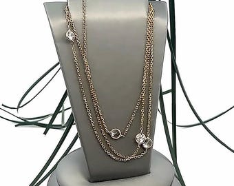 May include: A gold chain necklace with three clear round stones. The necklace is layered and is displayed on a gray stand.