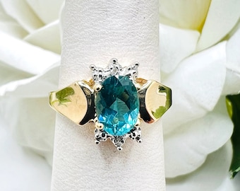 May include: A gold ring with a large oval blue gemstone surrounded by smaller white gemstones.