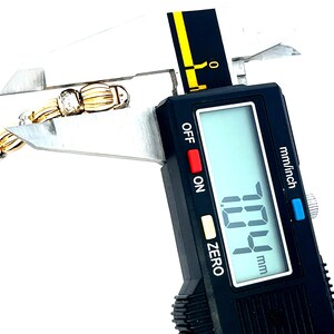 May include: A close-up of a digital caliper measuring a gold chain with a diamond accent. The caliper reads 7.04 mm.
