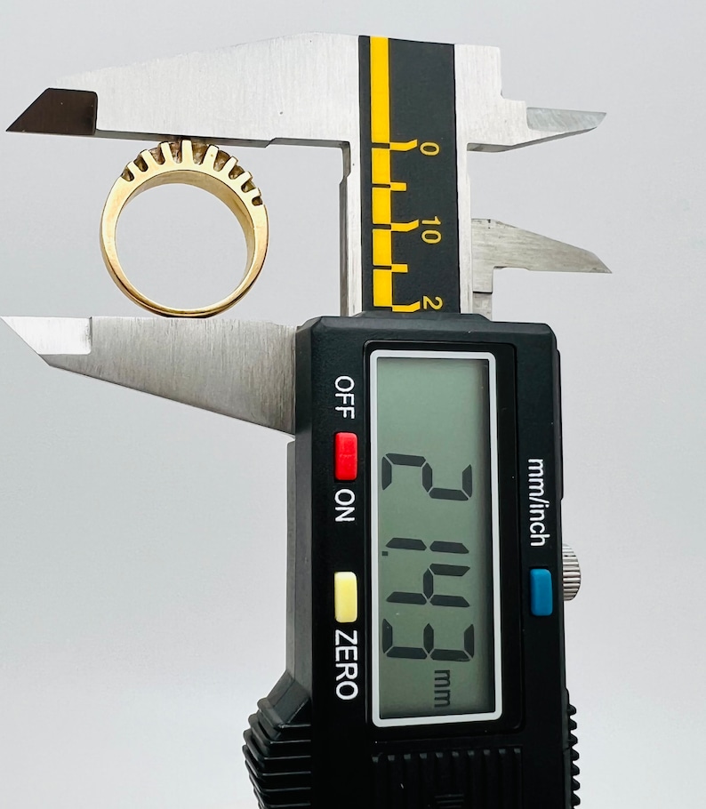 May include: A digital caliper measuring a gold ring with a textured surface. The reading on the display shows 2.15 mm.