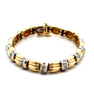 May include: A gold and white bracelet with a row of small diamonds set in each link. The bracelet has a clasp closure.