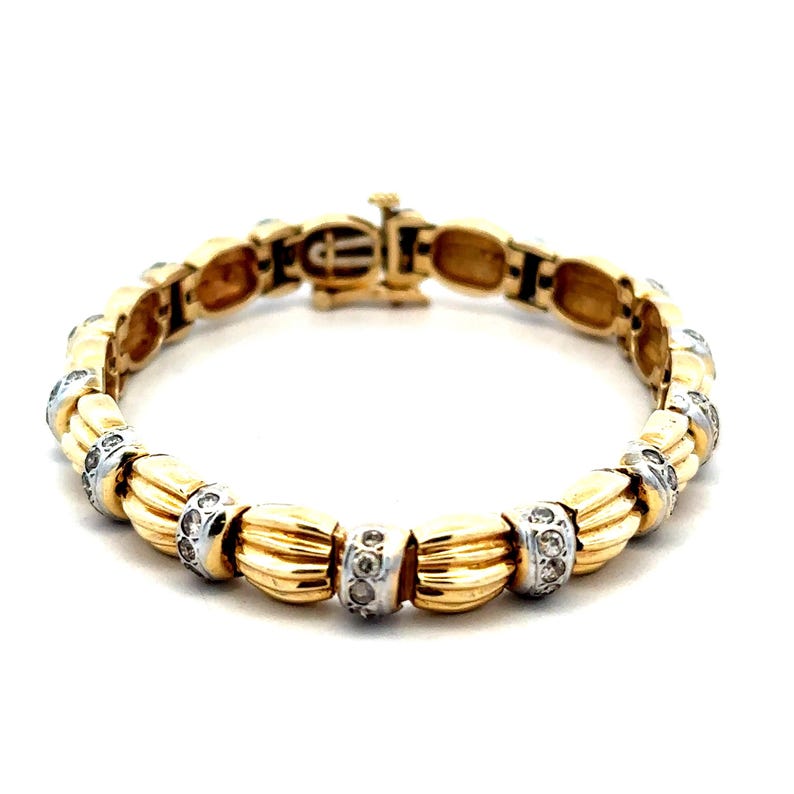 May include: A gold and white bracelet with a row of small diamonds set in each link. The bracelet has a clasp closure.