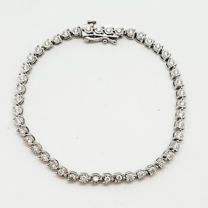 May include: A silver tennis bracelet with a row of round, clear diamonds.