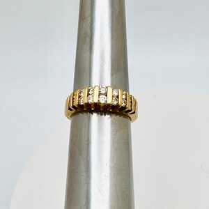May include: A gold band ring with a row of small, clear diamonds.