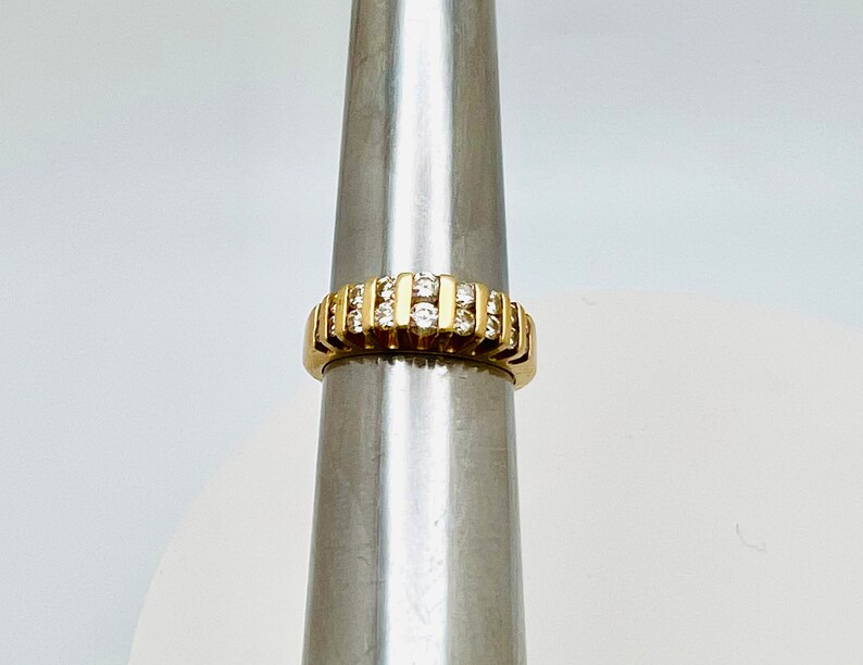 May include: A gold band ring with a row of small, clear diamonds.