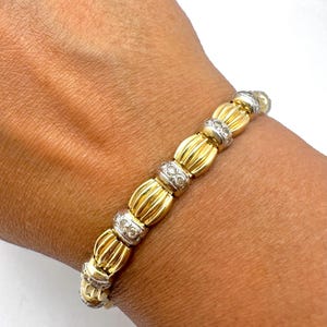 May include: A gold and white bracelet with a series of round, diamond-encrusted links. The bracelet is made of 18k gold and features a classic design.