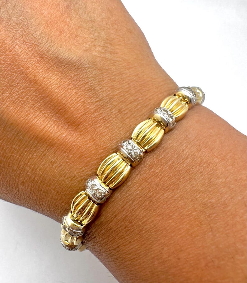 May include: A gold and white bracelet with a series of round, diamond-encrusted links. The bracelet is made of 18k gold and features a classic design.