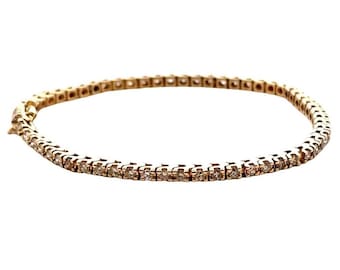 May include: A gold tennis bracelet featuring a continuous line of small, clear gemstones. The bracelet is circular and crafted from a warm-toned gold metal. The gemstones are set closely together, creating a sparkling effect.