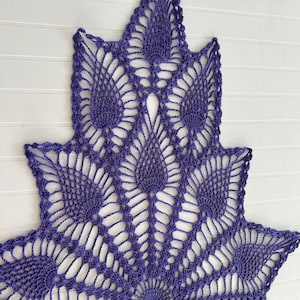 Puede incluir: Un gran encaje de ganchillo de color morado con un patrón de estrella. El encaje está hecho con puntadas delicadas e intrincadas y tiene un diseño de encaje abierto.