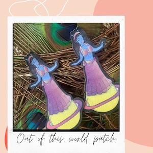 May include: Two colourful iron-on patches featuring a blue-skinned figure in a purple dress standing on a yellow planet. The text "Out of this world patch" is at the bottom of the image.