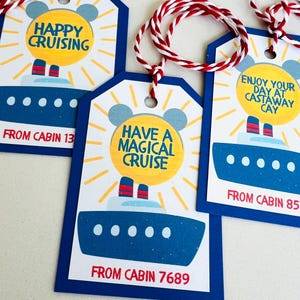 May include: Gift tags with a blue cruise ship design and the phrases "Happy Cruising", "Have a Magical Cruise", and "Enjoy Your Day at Castaway Cay". Each tag has a red and white string for hanging.
